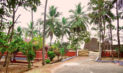 贝格尔ShriGo Bekal Fort Resort & Spa的庭院里种有棕榈树,设有红色的围栏