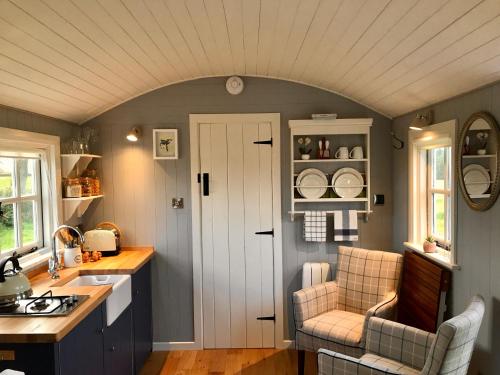 卡文Sheelin Shepherds Hut的厨房设有白色的门和两把椅子