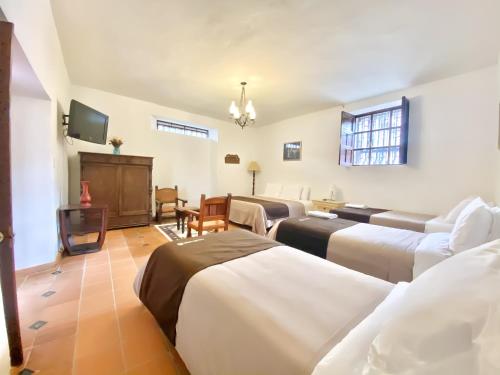莱瓦镇Casa del Carmen - Villa de Leyva的一间带几张床和电视的客厅