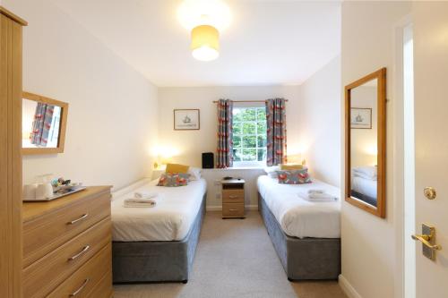 布德布兰登阿姆斯酒店的一间卧室设有两张床、一个水槽和镜子