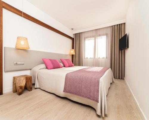 卡拉塔瑞达Insotel Club Tarida Playa的卧室配有一张带粉红色枕头的大床