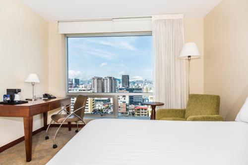 基多基多智选假日酒店的配有一张床、一张书桌和一扇窗户的酒店客房