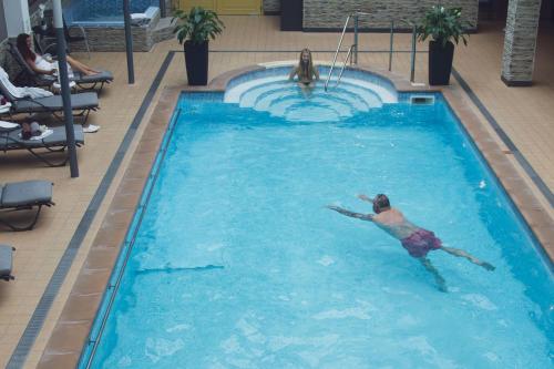 新赫拉迪Wellness hotel Rezidence的在酒店游泳池游泳的人