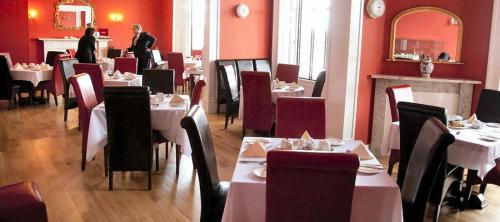 勒威克The Grand Hotel的用餐室设有白色桌子和红色墙壁