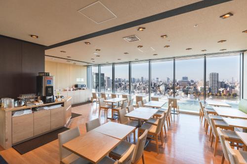 东京Hotel Crown Hills Ueno Premier的餐厅设有桌椅和大窗户。