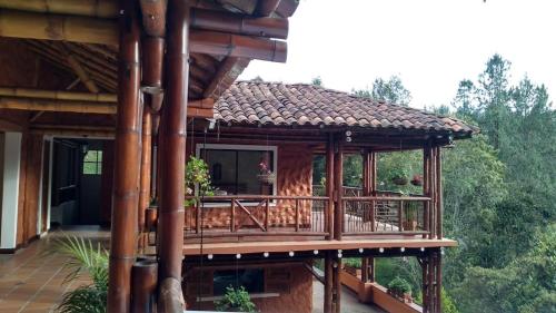 麦德林La Casona Del Retiro的木房子,在树林里设有甲板