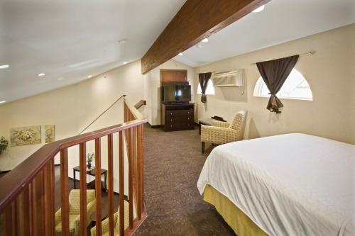 希尔城AmericInn by Wyndham Hill City Mt Rushmore的一间卧室设有一张床,楼梯配有电视。