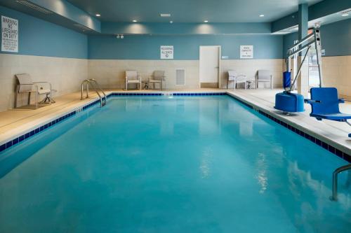 梅德福Holiday Inn Express & Suites - Medford, an IHG Hotel的一个带蓝色水和椅子的游泳池