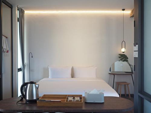 清迈Wonderwall Hotel的卧室配有白色的床和木桌