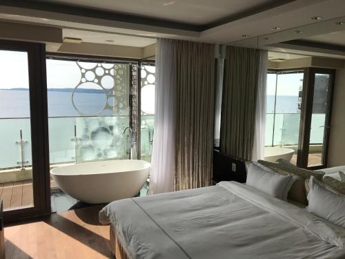 西归浦市Ocean Star Condominium的一间带浴缸和大窗户的卧室