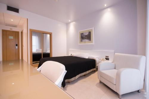 卢戈Hotel Auditorio Santiago & Spa的一间卧室配有一张床和两把白色椅子