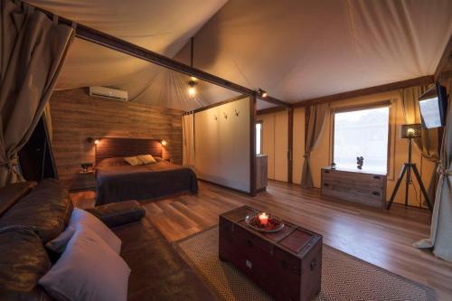 大洛希尼Glamping Tents and Mobile Homes Trasorka的帐篷内的房间,配有一张床和一张沙发