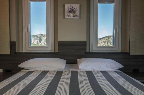 Borgo AdornoForesteria La Merlina的窗户间内的一张带两个枕头的床