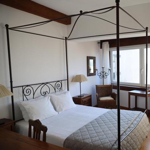 波尔图珀尔特弗兹酒店的一间卧室配有一张天蓬床和一把椅子