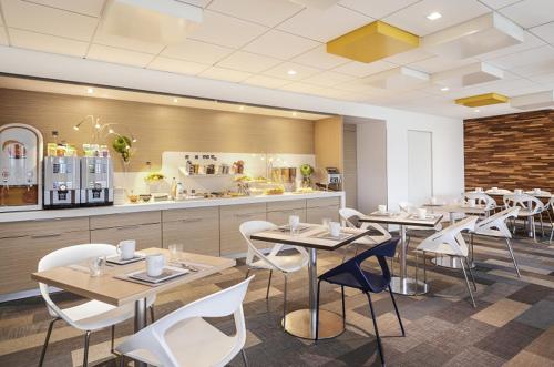 勒芒基里亚德东勒芒酒店的餐厅设有桌子、白色椅子和柜台