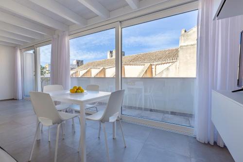 特拉帕尼Le Cupole Suites & Apartments的配有大窗户的客房内的白色桌子和椅子