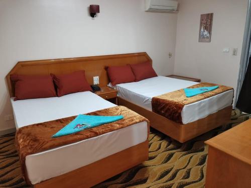 Damanhûrفندق جراند كليوباترا دمنهور的两张位于酒店客房的床,配有蓝色餐巾