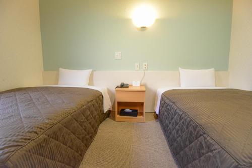 东京Kamata Inn Social的酒店客房设有两张床和床头柜。