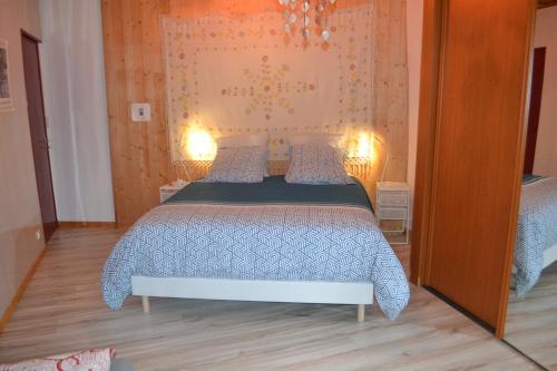 Égliseneuve-près-Billomstudio indépendant dans maison à la campagne的一间卧室配有一张带蓝色被子的床和两盏灯。