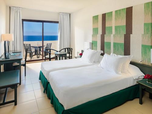 下布雷尼亚H10塔布恩特海滩酒店的一间卧室设有一张大床,享有海景