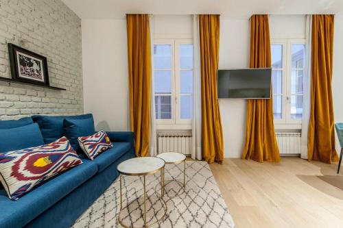 马德里Hauzify I Apartamento Salamanca的客厅配有蓝色的沙发和橙色窗帘