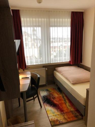 富尔达曼德法赫特皮特彻斯酒店的一间卧室配有一张床、一张书桌和一个窗户。