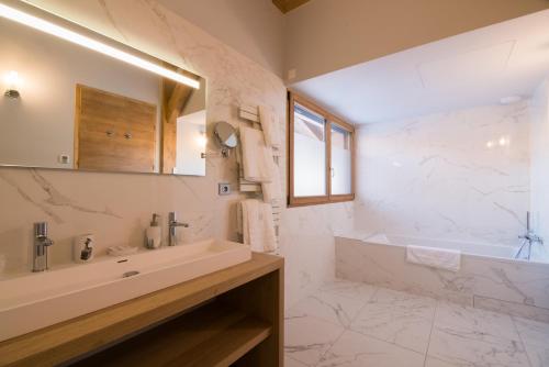 阿尔利河畔普拉兹Les Portes de Megève的白色的浴室设有浴缸和水槽。