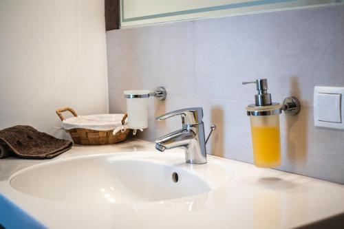 圣洛伦佐-迪塞巴托Apartment CANUS - Krumas Living - Kronplatz的浴室水槽配有水龙头和一杯橙汁