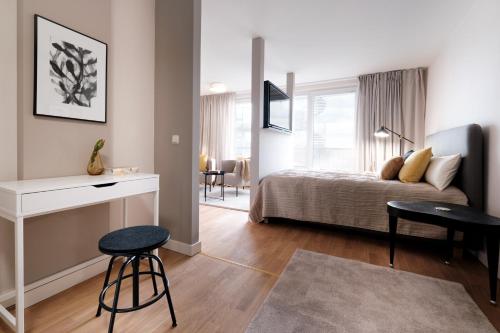 莱比锡SAXX Apartments Leipzig的一间卧室配有一张床、一张桌子和凳子