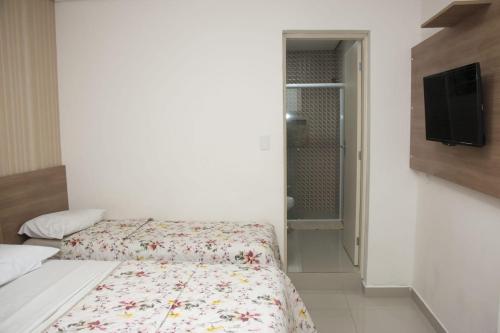 瓜鲁雅Hotel Morada do Mar的一间带床和电视的小卧室