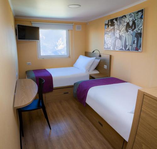 卡拉马Hotel Modular Express Calama的小房间设有两张床和一张桌子