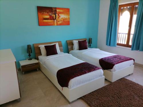 希法Le Sifah - Marina View Apartments & Villa的蓝色墙壁客房的两张床