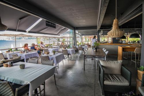 阿拉尼亚Sun Hotel By En Vie Beach的一间设有桌椅的餐厅,有人坐在餐厅里
