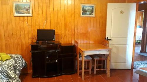 科伊艾科Apart Hotel Arrayán的客房设有桌子和带电视的书桌。