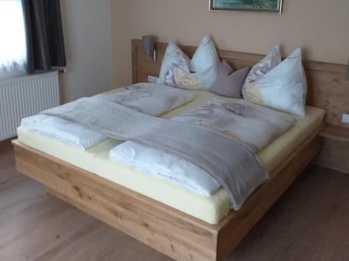 特洛普拉赫Ferienwohnung-Nassfeld-Haus Umschaden的一张带白色床单和枕头的大型木制床