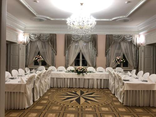 亚斯琴别-兹德鲁伊玻璃尼亚宫酒店的宴会厅配有白色的桌椅和吊灯