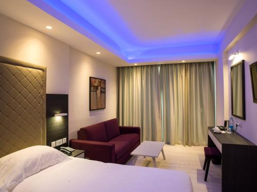 拉纳卡弗兰吉奥酒店的酒店客房配有一张床、一把椅子和一张沙发