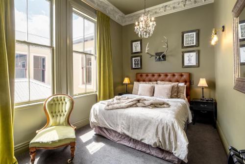 FeatherstonThe Royal Hotel Featherston - Boutique Hotel的一间卧室配有一张床、一把椅子和一个吊灯。