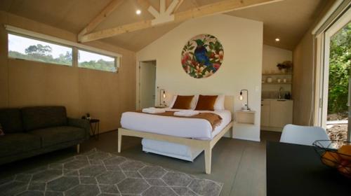 欧尼罗亚One O One Cabins, Waiheke Island的一间卧室配有一张床和一个沙发