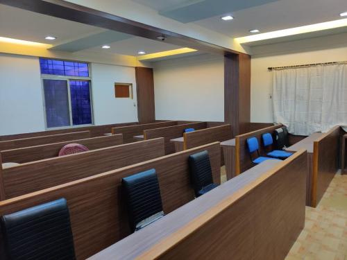 乌杜皮Bedspace Living的配有木制长椅和蓝色椅子的审判室