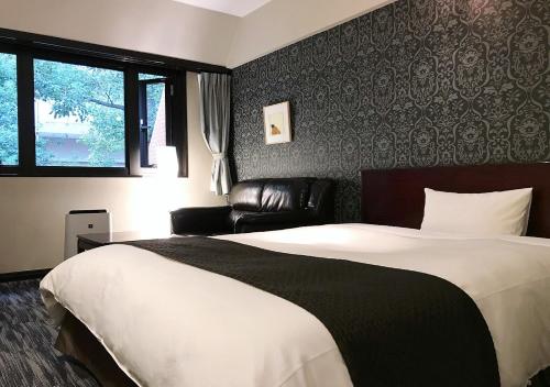 熊本奥库斯酒店的一间卧室配有一张大床和一张皮沙发