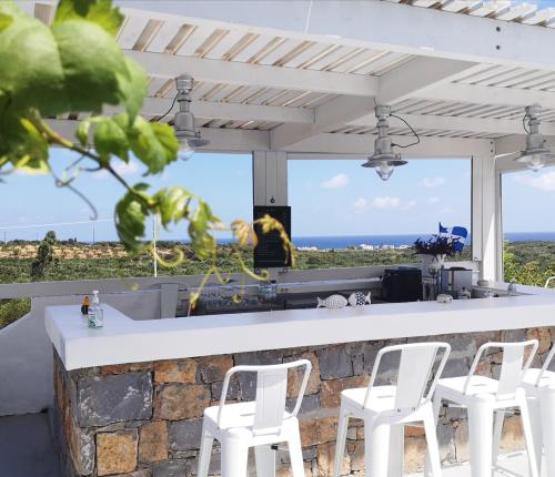 莫拉托斯Milatos Village Cretan Agrotourism Hotel的一间酒吧,配有白色椅子,享有海景