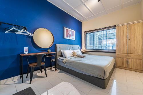 吉隆坡3BR Family-Friendly Landed House,PandanPerdana,KL by Verano的一间卧室设有蓝色的墙壁、一张床和一张书桌