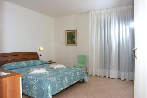 托尔托雷托Verde Mare "Appartamenti per Vacanze"的一间卧室配有一张床和一把绿色椅子