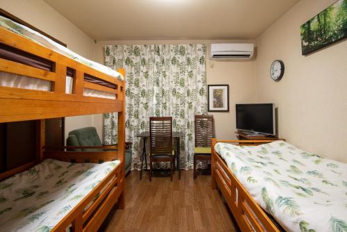 日光Garden Nikko Guest House的一间卧室配有两张双层床和电视