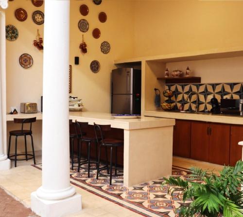 梅里达Hotel & Hostal Boutique Casa Garza的厨房配有带凳子的柜台和冰箱。