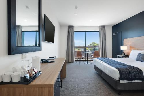 纽卡斯尔Springs Newcastle的配有一张床和一张书桌的酒店客房