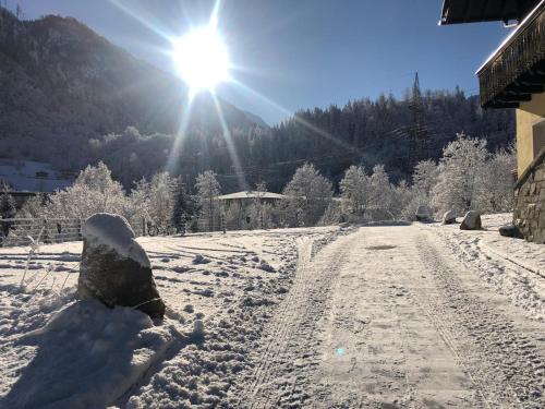 卡普伦AlpinResort Kaprun 2的一条有雪覆盖的道路,在背后有太阳