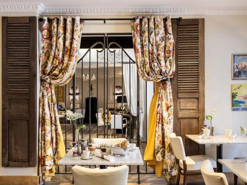 皇后镇皇后镇索菲特酒店及水疗中心的用餐室配有桌椅和窗帘