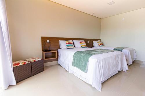 戈亚斯州上帕莱索Villa Tereza的一间卧室配有两张带白色床单的床